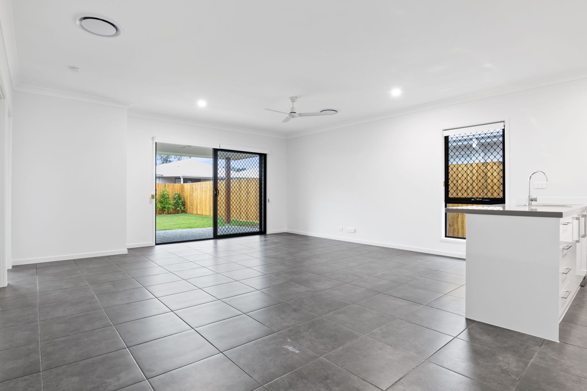 Bright and empty modern living room with sliding doors and tiled floor.